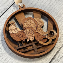 Load image into Gallery viewer, Three-layered Christmas ornament, approximately 4" in diameter, made of multiple hardwood veneers, depicting a fancy rooster sitting on a barnyard fence with sun rays in the background. Made in Virginia by @BelCreativeArts.