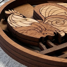 Load image into Gallery viewer, Three-layered Christmas ornament, approximately 4" in diameter, made of multiple hardwood veneers, depicting a fancy rooster sitting on a barnyard fence with sun rays in the background. Made in Virginia by @BelCreativeArts.