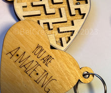 Load image into Gallery viewer, Valentine's Day gift, heart-shaped wooden maze puzzle with metal bead and clear acrylic top, with attached metal ring and colorful tassel by @belcreativearts